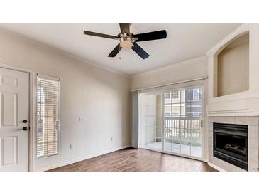 Bright living room featuring wood floors, ceiling fan, and sliding glass doors to a private patio at 10165 E Carolina Pl # 102, Aurora, CO 80247