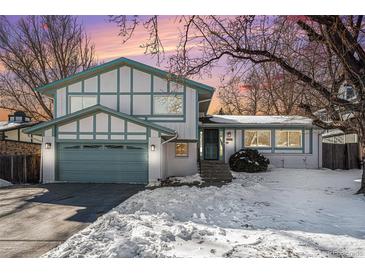 Two-story home with a green door and attached garage, nestled on a snow-covered lot at 2527 S Coors St, Lakewood, CO 80228