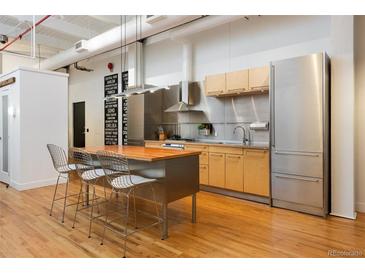 Modern kitchen with stainless steel appliances, a wood island and hardwood flooring at 2955 Inca St # 2F, Denver, CO 80202