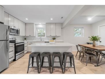 Bright kitchen features white cabinets, stainless steel appliances, and center island with bar seating at 1645 Wabash St, Denver, CO 80220