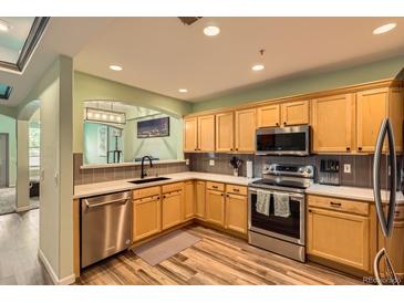Well-lit kitchen featuring stainless steel appliances, quartz countertops, and wood-look flooring at 1727 N Pearl St # 107, Denver, CO 80203