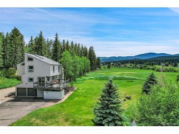 Charming two-story home featuring a spacious deck overlooking a lush green landscape with mountain views at 7614 Malamute Dr, Evergreen, CO 80439