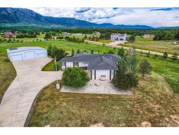 Stunning aerial view of a home with a large garage, and mountain views with rolling hills and scattered homes in the background at 16710 Vincent Ave, Monument, CO 80132