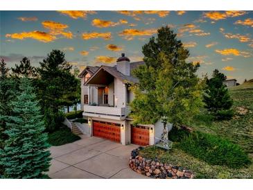 Charming home features a covered porch and two-car garage, surrounded by mature trees and lush landscaping at 386 Monte Vista Rd, Golden, CO 80401