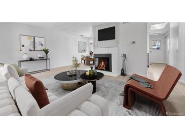 Bright living room featuring a fireplace and light wood floors at 264 S Newark Cir, Aurora, CO 80012