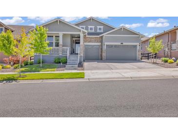 Charming two-story home with a well-manicured lawn and a two-car garage, stone accents, and inviting front porch at 8772 S Sicily Ct, Aurora, CO 80016