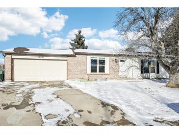 Brick ranch home with attached two-car garage and snowy front yard at 10975 Birch Dr, Thornton, CO 80233