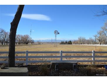 Scenic property view features an expansive field, a white fence, and a vintage windmill against a clear, blue sky at 7250 County Road 5, Erie, CO 80516