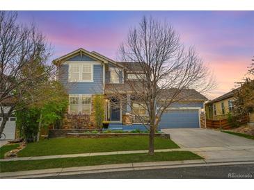 Charming two-story home featuring a blend of blue siding and stone accents with a well-manicured lawn at 15767 E 109Th Ave, Commerce City, CO 80022