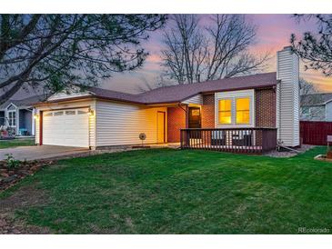 Charming home featuring a well-manicured lawn, front porch, and attached two-car garage at 12432 Bellaire St, Thornton, CO 80241