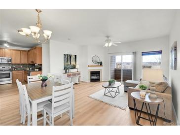 Open-concept living and dining area with a fireplace, light hardwood floors, and bright natural light at 10149 W 55Th Dr # 101, Arvada, CO 80002