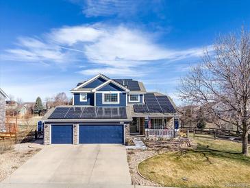 Charming two-story home with a blue exterior, three-car garage, manicured lawn and solar panels at 730 Pope Dr, Erie, CO 80516