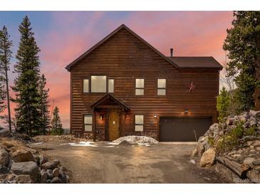 Charming log home with a two-car garage and inviting curb appeal against a colorful sky at sunset at 72 Overlook Ct, Idaho Springs, CO 80452