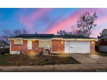 Charming single-story brick home featuring a two-car garage, solar panels, and cozy front porch, and nice landscaping at 8140 Pennsylvania Way, Denver, CO 80229