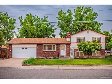 Charming two-story home with brick and white siding, a well-maintained lawn, and an attached two car garage at 1583 Skeel St, Brighton, CO 80601