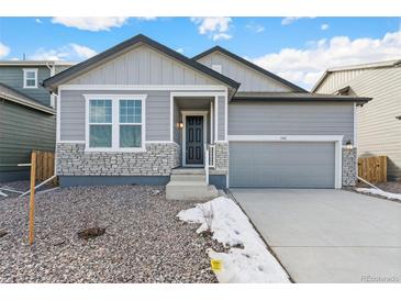 Gray exterior boasts a two-car garage and stone accents at 13412 E 110Th Way, Commerce City, CO 80022