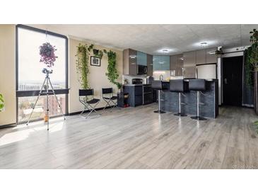 Bright, modern kitchen featuring stainless steel appliances, stone counter tops, and breakfast bar in sunlit room with city views at 1301 Speer Blvd # 1108, Denver, CO 80204
