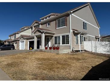 Charming two-story home featuring a covered porch, red potted plants, and a well-manicured lawn at 21561 E 48Th Pl, Denver, CO 80249