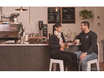 Warm coffee shop interior with a couple seated at the bar, coffee equipment, and a cozy atmosphere at 10115 W 25Th Ave # 1, Lakewood, CO 80215