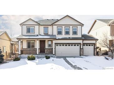 Charming two-story home with a three-car garage and snow-covered front yard at 21572 E Union Dr, Aurora, CO 80015