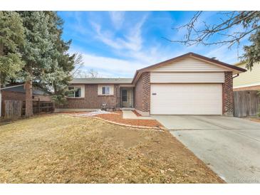 Charming brick home with a two-car garage and a well-manicured lawn on a sunny day at 15104 E Utah Pl, Aurora, CO 80012