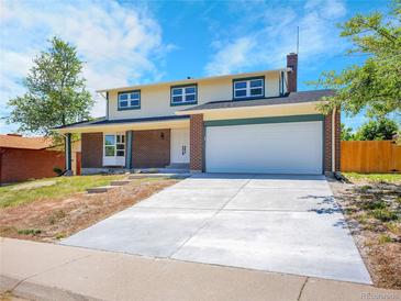 Charming two-story home featuring a brick facade, two-car garage, and a well-maintained front yard at 8694 E Eastman Ave, Denver, CO 80231