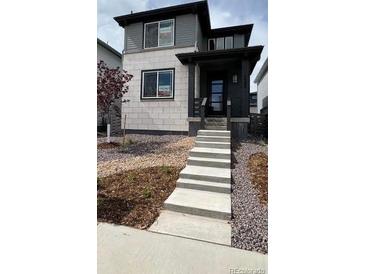 Two-story home featuring a mix of stone and gray siding and a welcoming front porch at 7360 Watercress Dr, Littleton, CO 80125