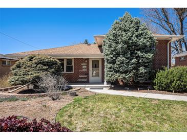 Charming brick home with a manicured lawn, mature trees, and inviting walkway at 6305 Yukon St, Arvada, CO 80004