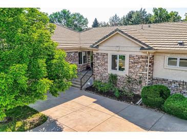 Beautiful stone and stucco home with a well-manicured yard and tile roof at 14064 E Whitaker Dr, Aurora, CO 80015