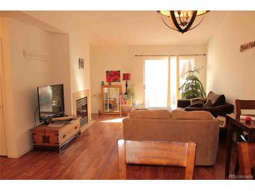 Bright living room features wood floors, a fireplace, and sliding glass doors to the outside at 8112 Gray Ct # 394, Arvada, CO 80003