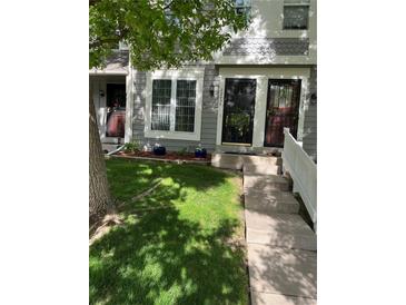 Charming townhome featuring a well-maintained lawn, concrete walkway, and gray siding with decorative trim at 2285 S Jasper Way # A, Aurora, CO 80013