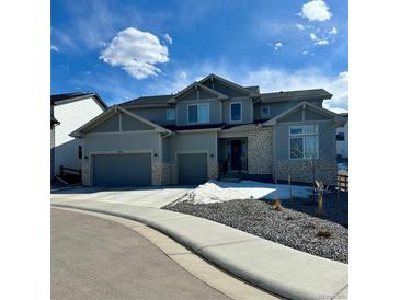 Attractive two-story home featuring a two-car garage, stone accents, and manicured landscaping under a cloudy blue sky at 5411 Edenborn Way, Castle Rock, CO 80104
