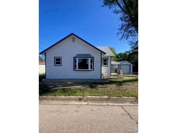 Charming single-story home with white siding, a blue trim, and a detached garage at 521 10Th St, Fort Lupton, CO 80621