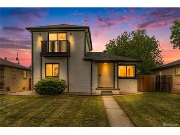 Charming two-story home features a front yard, balcony, and freshly painted white brick exterior at 3550 Eudora St, Denver, CO 80207