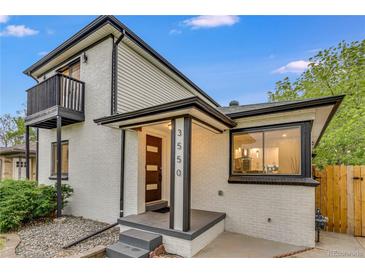 A modern home has a painted brick exterior with black trim and a balcony overlooking the front yard at 3550 Eudora St, Denver, CO 80207