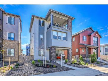 Inviting two-story home featuring a covered porch and second-story balcony with stone and blue-grey siding accents at 8728 Hotchkiss St, Littleton, CO 80125