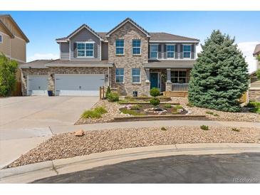 Charming two-story home with a well-maintained lawn, brick accents, and a two-car garage and inviting front porch at 11921 S Black Horn Cir, Parker, CO 80134