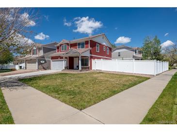 Charming two-story red home featuring a well-manicured lawn and bright white fence at 5552 Odessa St, Denver, CO 80249