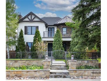 Beautiful two-story home with a stone and wrought iron fence and manicured landscaping at 2646 S Madison St, Denver, CO 80210
