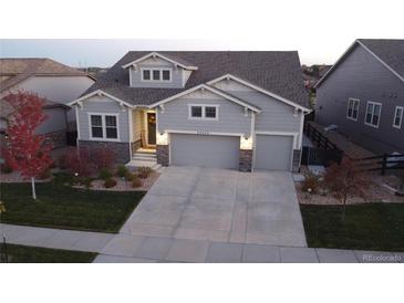 Two-story craftsman style home with gray siding, stone accents, and a three-car garage at 23542 E Bailey Pl, Aurora, CO 80016