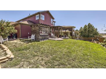 Landscaped backyard featuring a wooden pergola and patio, ideal for outdoor relaxation and entertaining at 10811 Chambers Way, Commerce City, CO 80022