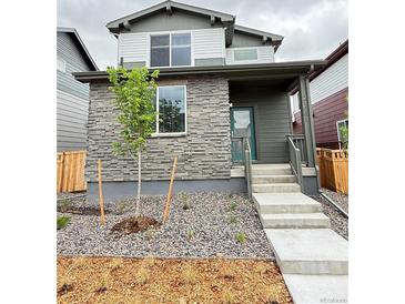 Inviting two-story home featuring stone accents, an easy-to-maintain yard, and a charming front porch at 21081 E 63Rd Dr, Aurora, CO 80019