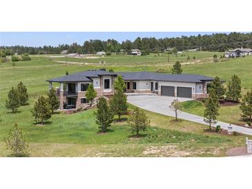 View of home featuring gray roof, outdoor patio, stone facade, manicured lawns, and garage at 2937 Hidden Den Ct, Franktown, CO 80116