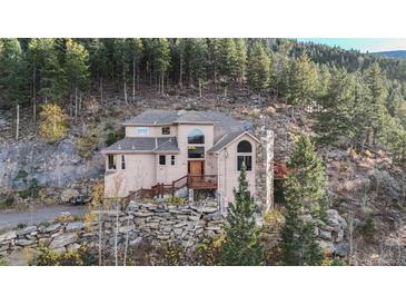 Secluded mountain home with stone accents and wooden deck nestled amongst trees at 900 Sawmill Creek Rd, Evergreen, CO 80439