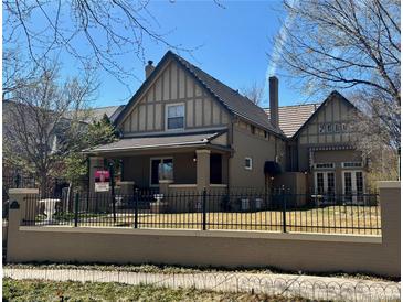 Charming two-story home featuring a well-maintained lawn and secure black metal fence at 1751 Clermont St, Denver, CO 80220