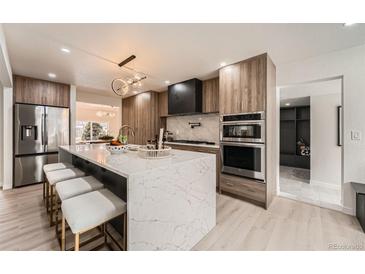 Bright kitchen features marble waterfall island, stainless steel appliances, and wood grain cabinets at 4055 S Niagara Way, Denver, CO 80237