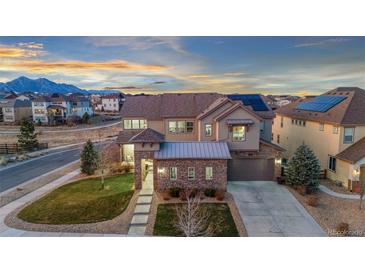 Beautiful two-story home featuring stone accents, a well-manicured lawn, and mountain views in the background at 19495 W 94Th Ave, Arvada, CO 80007
