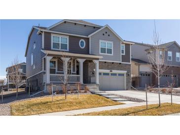 Charming two-story home featuring a covered porch, stone accents, and a two-car garage at 8240 S White Crow St, Aurora, CO 80016