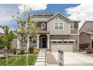 Charming two-story home featuring stone accents, a welcoming porch, and a well-manicured lawn at 8240 S White Crow St, Aurora, CO 80016