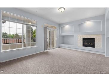 Bright living room with fireplace and access to a balcony through sliding glass doors at 12711 Colorado Blvd # 1116, Thornton, CO 80241